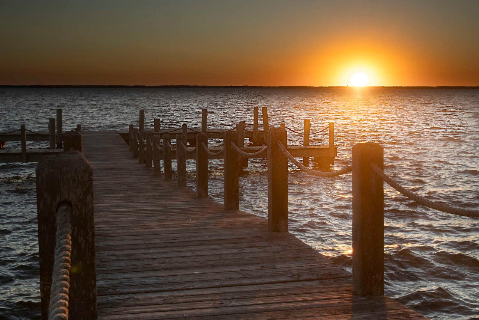 Sunset over the sound from a weathered dock in Duck, North Carolina